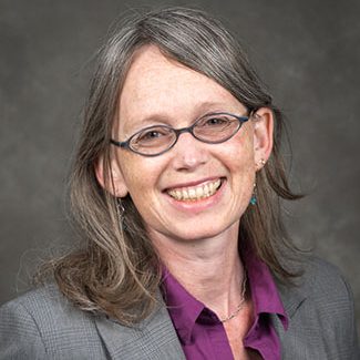 A photo of Rozalyn Anderson, Phd, wearing a grey suit and a purple shirt.